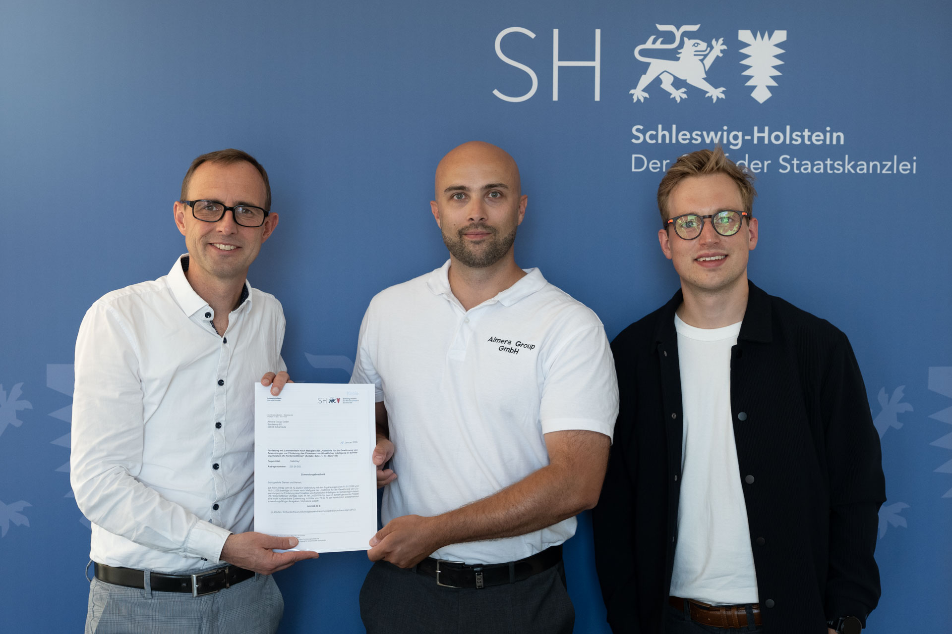 Dirk Schrödter (links) übergibt Dr.-Ing. Lino Griefer (Mitte) den Zuwendungsbescheid für das Projekt. Rechts daneben steht eine weiterePerson von Linus Prinz (rechts).