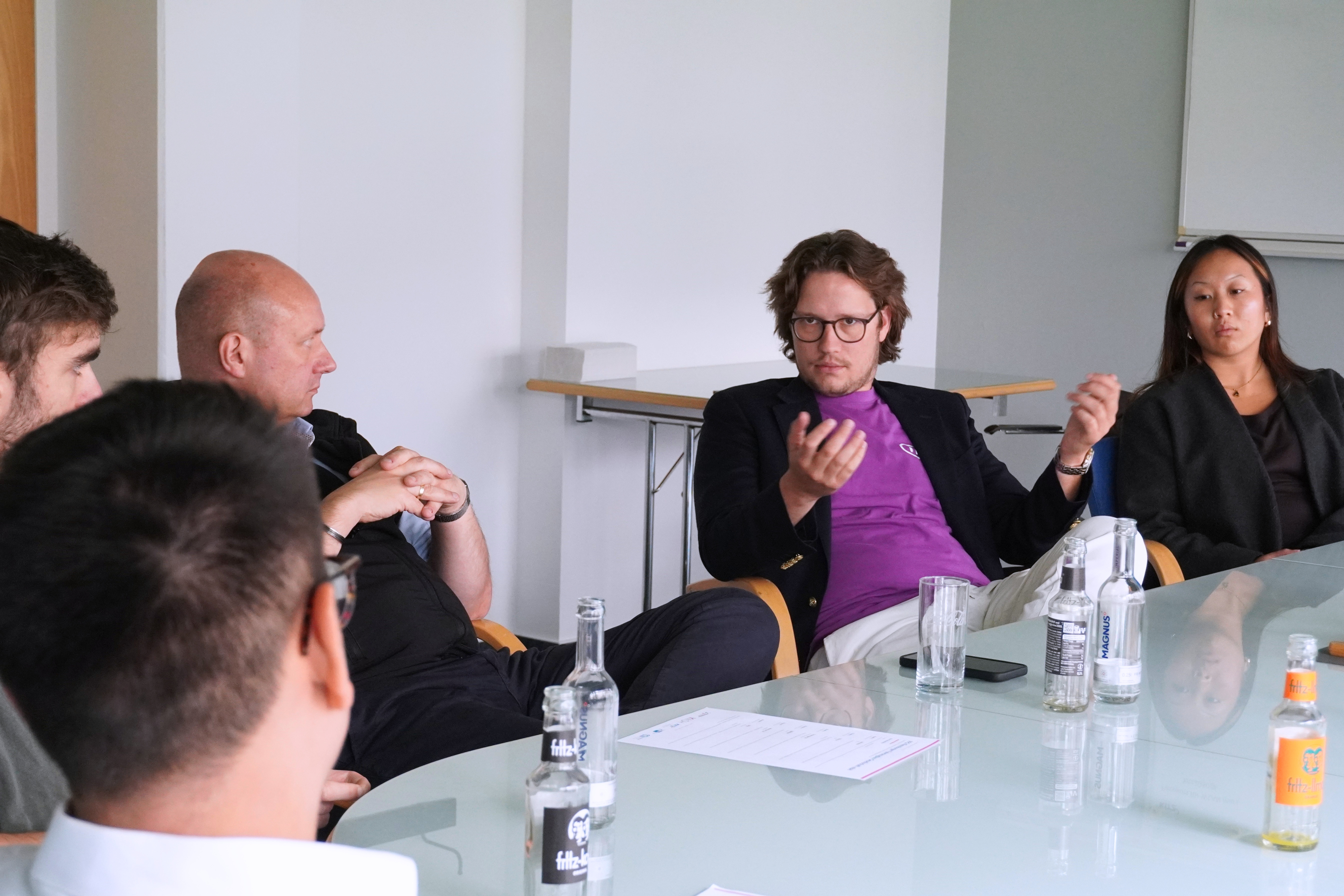 fünf Personen sitzen an einem Konferenztisch im Gespräch