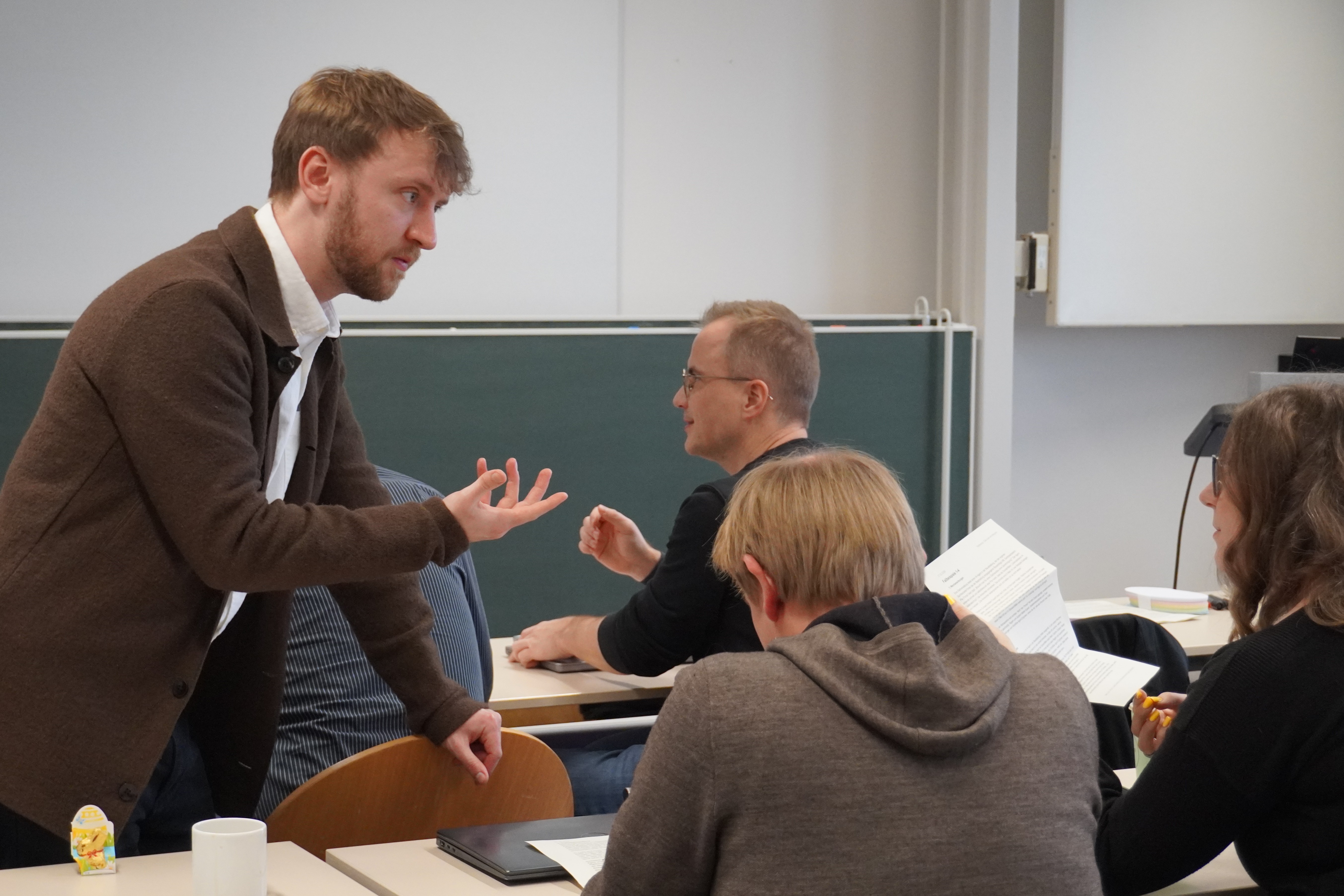 Ein Mann steht an einem Tisch und erklärt etwas
