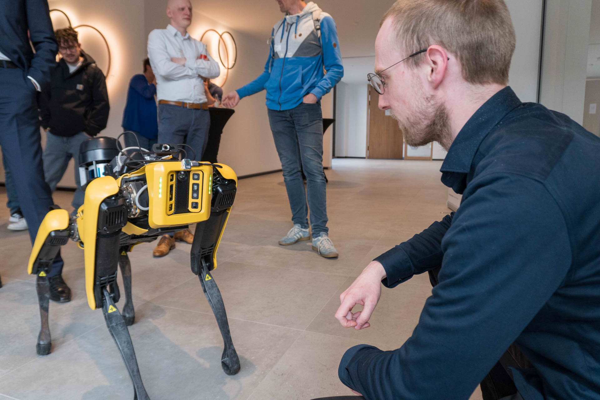 Ein Mann hockt vor einem gelben Roboterhund